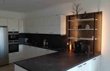 Küchenstudio Eine Küche mit einer schwarzen Arbeitsplatte und Geräten aus Edelstahl.