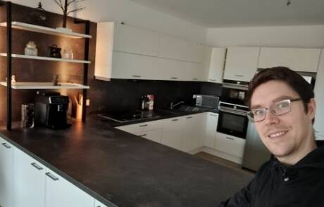 Küchenstudio Ein Mann mit Brille steht vor einer Küche.