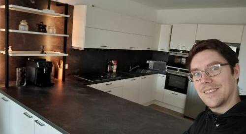 Küchenstudio Ein Mann mit Brille steht vor einer Küche.