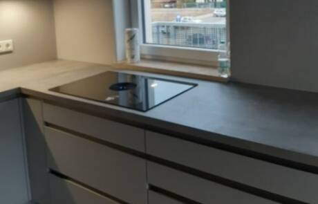 Küchenstudio Eine Küche mit grauen Schränken und einem Fenster.