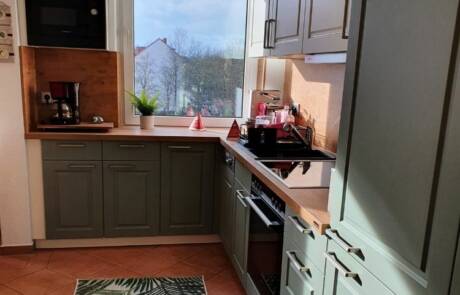 Küchenstudio Eine Küche mit grünen Schränken und einem Fenster.