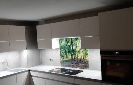 Küchenstudio Eine weiße Küche mit Blick auf einen Wald.