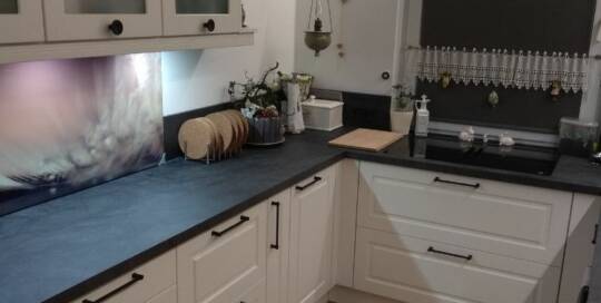 Küchenstudio Eine Küche mit weißen Schränken und schwarzen Arbeitsplatten.