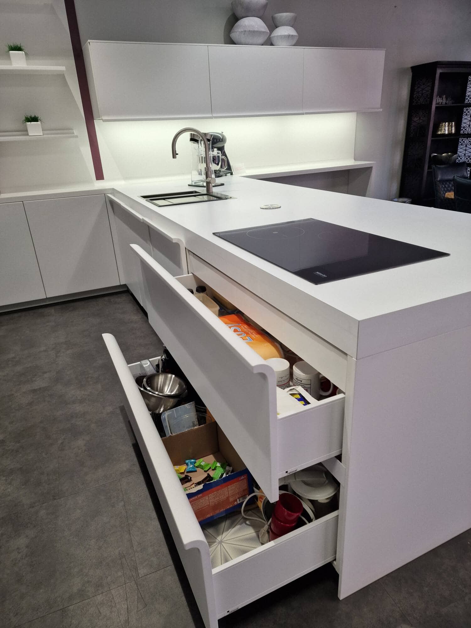 Küchenstudio Eine weiße Küche mit einer weißen Insel und Schubladen zum Abverkauf verfügbar.