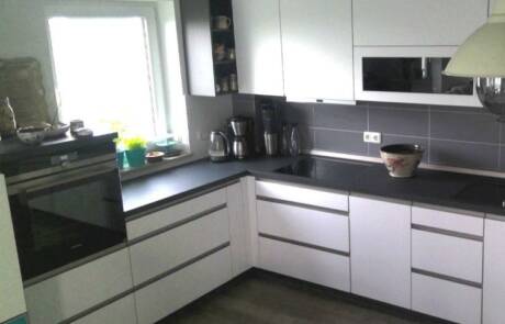 Küchenstudio Eine Küche mit weißen Schränken und schwarzen Geräten.