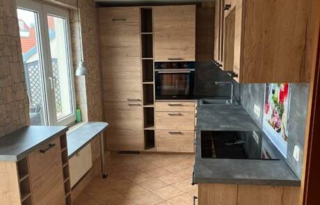 Küchenstudio Eine kleine Küche mit Holzschränken und einem Fenster.