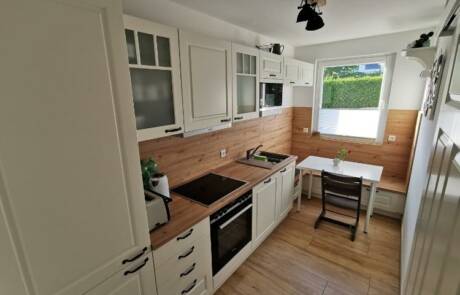 Küchenstudio Eine kleine Küche mit weißen Schränken und Holzböden.