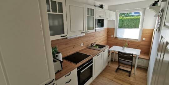 Küchenstudio Eine kleine Küche mit weißen Schränken und Holzböden.