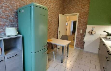Küchenstudio Eine kleine Küche mit einem grünen Kühlschrank und einem Tisch.