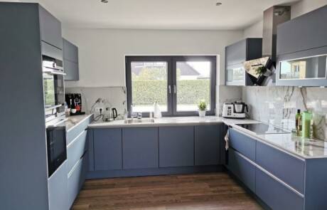 Küchenstudio Eine Küche mit blauen Schränken und Holzböden.