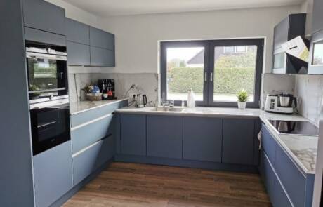 Küchenstudio Eine Küche mit blauen Schränken und Holzboden.