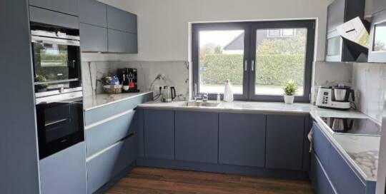 Küchenstudio Eine Küche mit blauen Schränken und Holzboden.