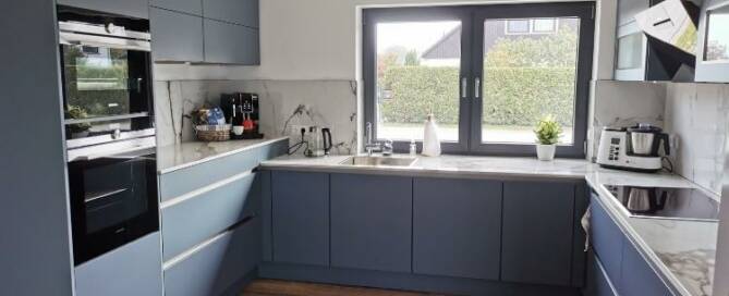 Küchenstudio Eine Küche mit blauen Schränken und Holzboden.