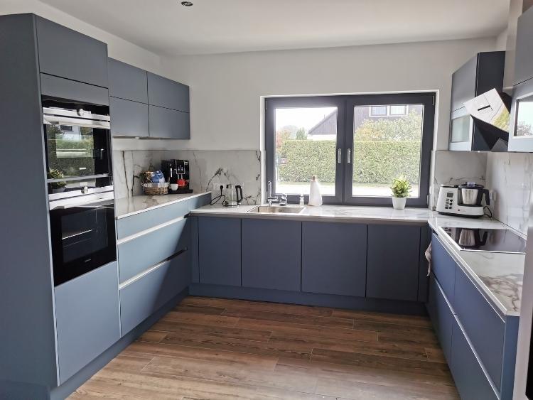 Küchenstudio Eine Küche mit blauen Schränken und Holzboden.