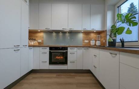Küchenstudio Eine weiße Küche mit Holzschränken und einem Holzofen.