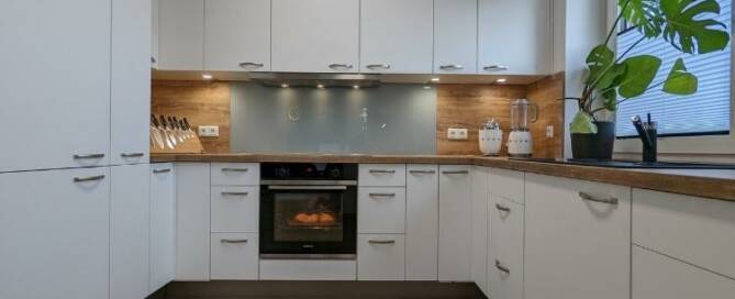 Küchenstudio Eine weiße Küche mit Holzschränken und einem Holzofen.