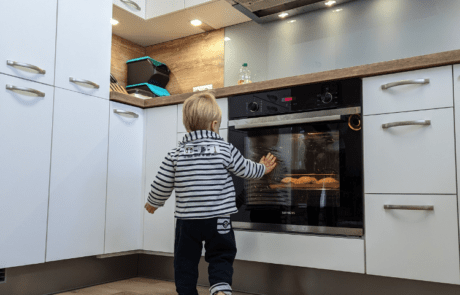 Küchenstudio Ein Kind steht vor einem Ofen.
