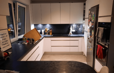 Küchenstudio Eine Küche mit weißen Schränken und schwarzen Arbeitsplatten.