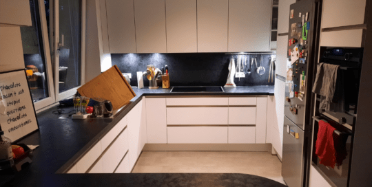 Küchenstudio Eine Küche mit weißen Schränken und schwarzen Arbeitsplatten.