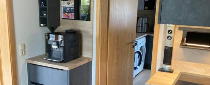 Küchenstudio Eine kleine Küche mit Kaffeemaschine und Kühlschrank.