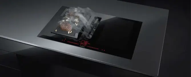 Küchenstudio Eine schwarze Herdplatte mit einem dampfenden Topf darauf in einem Küchenstudio.
