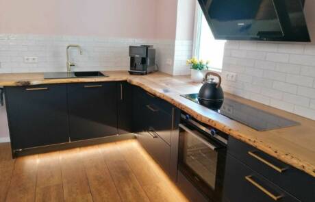Küchenstudio Eine Küche oder Küchenzeile mit schwarzen Arbeitsplatten und einem Fernseher.