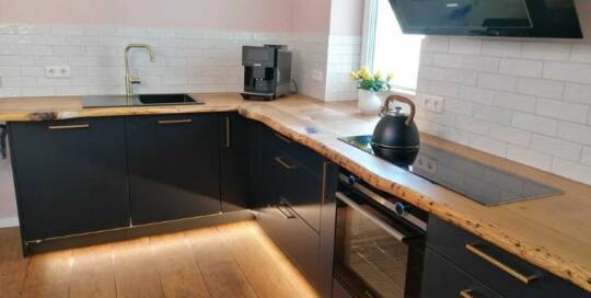 Küchenstudio Eine Küche oder Küchenzeile mit schwarzen Arbeitsplatten und einem Fernseher.