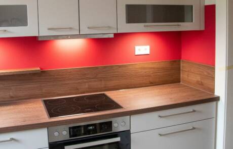 Küchenstudio Eine Küche mit weißen Schränken und roten Akzenten.
