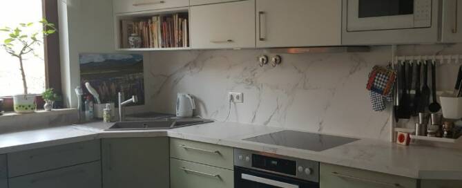 Küchenstudio Eine Küche mit weißen Schränken und grünen Arbeitsplatten.