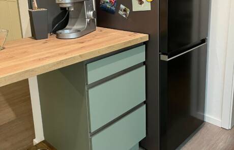 Küchenstudio Eine kleine Küche mit Kühlschrank und Kaffeemaschine.