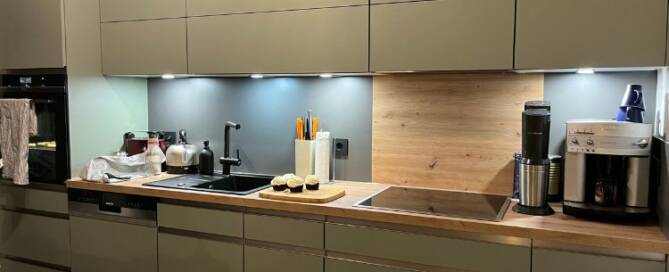 Küchenstudio Eine Küche mit grünen Schränken und Arbeitsplatten.