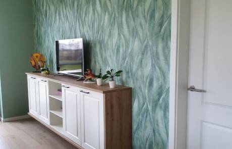 Küchenstudio Ein Wohnzimmer mit grüner Tapete und einem Fernseher.