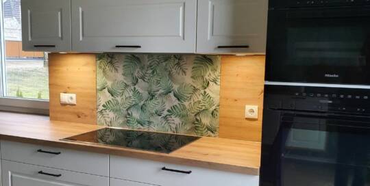 Küchenstudio Eine Küche mit weißen Schränken und einer grünen Rückwand.