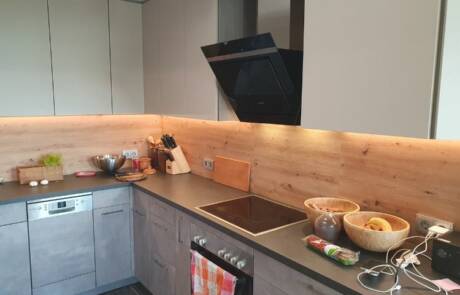 Küchenstudio Eine Küche mit einer Holzwand und einem Herd.