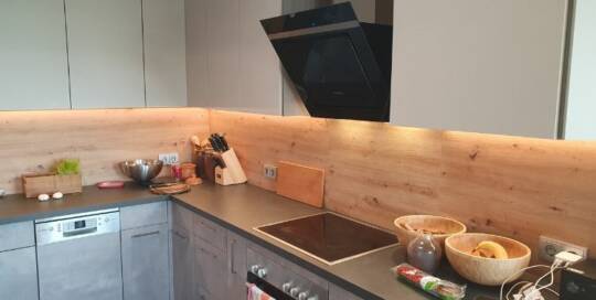 Küchenstudio Eine Küche mit einer Holzwand und einem Herd.