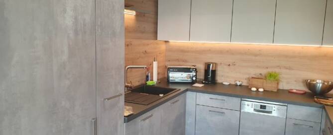 Küchenstudio Eine kleine Küche mit grauen Schränken und einem Waschbecken.