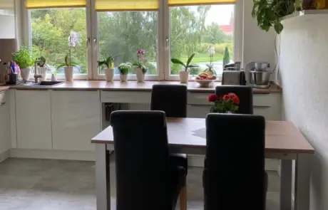 Küchenstudio Eine Küche mit Tisch und Stühlen und einem Fenster.