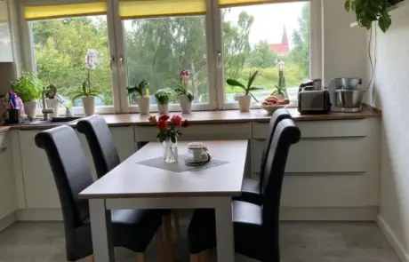 Küchenstudio Eine Küche mit Tisch und Stühlen vor einem Fenster.