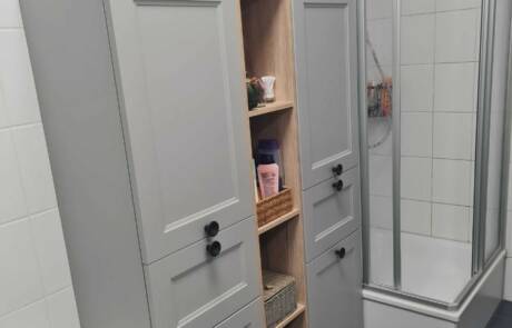 Küchenstudio Ein Badezimmer mit grauen Schränken und einer Dusche.