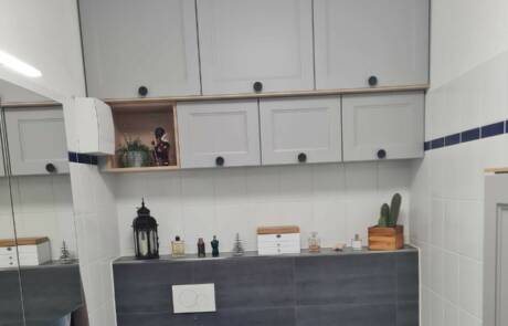 Küchenstudio Ein Badezimmer mit grauen Schränken und einer Toilette.
