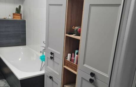 Küchenstudio Ein Badezimmer mit grauen Schränken und einer Badewanne.