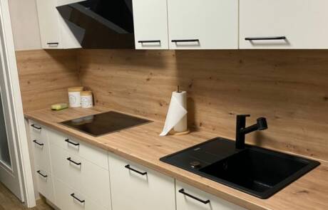 Küchenstudio Eine Küche mit einer Arbeitsplatte aus Holz und einem schwarzen Waschbecken.