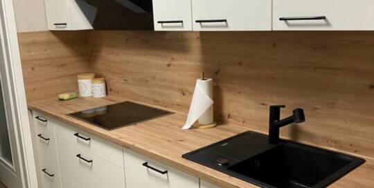 Küchenstudio Eine Küche mit einer Arbeitsplatte aus Holz und einem schwarzen Waschbecken.