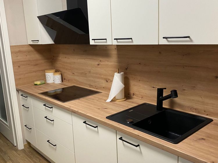 Küchenstudio Eine Küche mit einer Arbeitsplatte aus Holz und einem schwarzen Waschbecken.