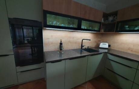 Küchenstudio Eine Küche mit grünen Schränken und einer Spüle.