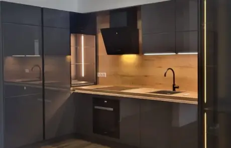 Küchenstudio Moderne Küche mit dunklen Schränken, Holzakzenten und Unterschrankbeleuchtung. Zur Ausstattung gehören ein schwarzer Wasserhahn, ein eingebauter Backofen und ein Herd. Holzboden ergänzt das Design.