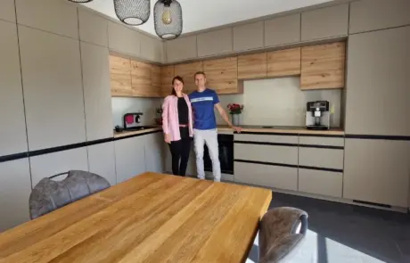 Küchenstudio Zwei Personen stehen zusammen in einer modernen Küche mit hellen und grauen Schränken, neben einem Esstisch aus Holz mit Stühlen.