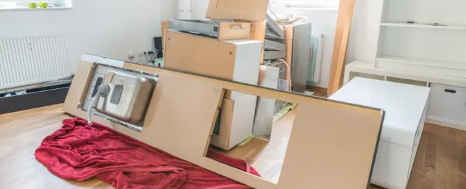 Küchenstudio Küchenschränke und eine Arbeitsplatte mit angeschlossener Spüle werden demontiert und zusammen mit anderen entfernten Einrichtungsgegenständen in einem zu renovierenden Raum auf den Boden gelegt.
