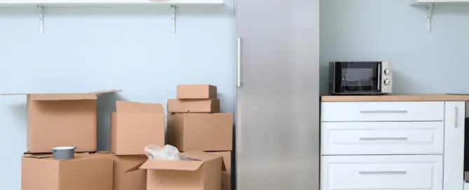 Küchenstudio In einer modernen Küche stapeln sich mehrere offene Kartons neben einem Edelstahlkühlschrank, was auf einen Umzug oder ein Auspacken hindeutet.