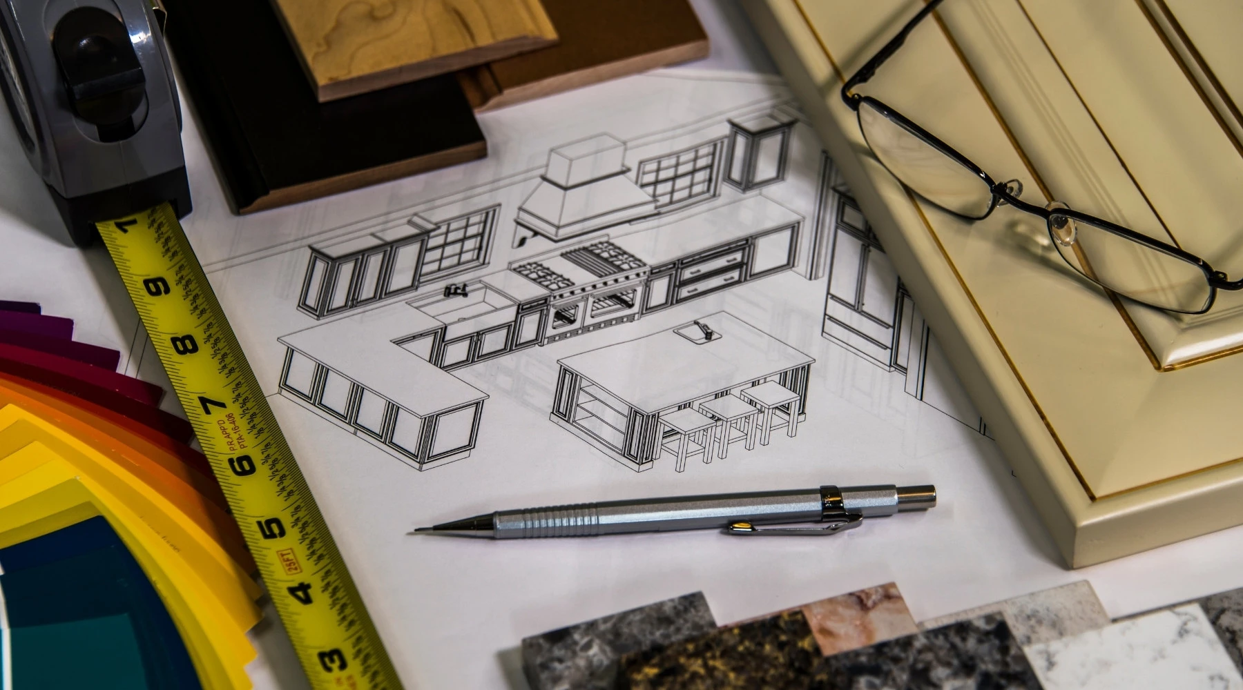 Küchenstudio Architektonischer Küchenentwurf, umgeben von einem Stift, einem Maßband, einer Brille, Farbmustern, Materialproben und Schranktürmustern.